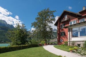 a house with a walkway next to a lake at Grand Hotel Molveno in Molveno