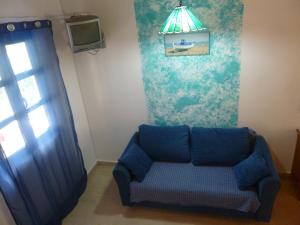 a living room with a blue couch and a tv at Athina Apartments in Arillas