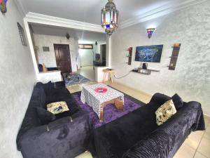 a living room with a black couch and a table at Appartement 6 personnes piscine hivernage Marrakech in Marrakesh
