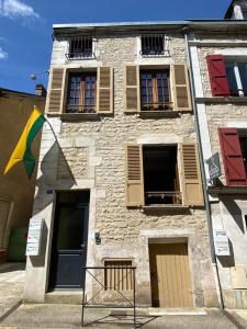 a stone building with windows and a flag at La Belle vigne - Chablis Centre in Chablis