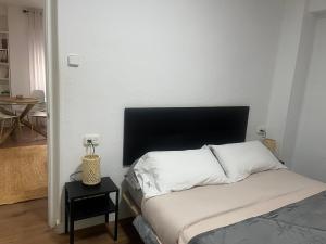 a bedroom with a bed with a black headboard and a table at Casa Bia Plus in Elche