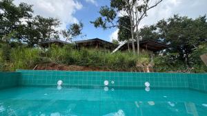 a blue tiled swimming pool with houses in the background at Three Tree Villa By Habarana in Habarana