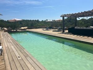 a large swimming pool with a wooden deck and benches at Lodges en pleine nature in Riez