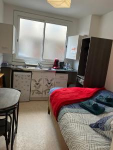 a bedroom with a bed and a table and a kitchen at L’esprit libre in Lacaune