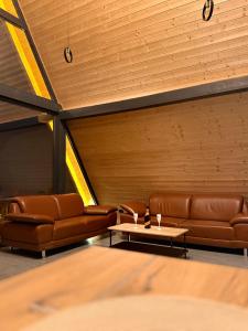 a waiting room with brown leather couches and a table at ALTURA Chalet in Muntele Băişorii +8 photos