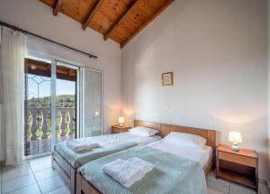 a bedroom with two beds and a large window at Villa Amalia By Elayan Villas Corfu in Karousádes