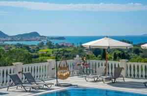 a patio with chairs and an umbrella and a pool at Villa Amalia By Elayan Villas Corfu in Karousádes