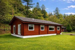 a small cabin in the middle of a yard at Antler Lodge Traditional Log Cabin in Dunoon