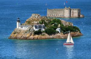 a sailboat in the water in front of a castle at Chez Ninie in Le Cloître-Saint-Thégonnec