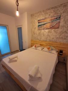 a bedroom with a large white bed with towels on it at Apartament DelyMar in Agigea