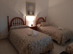 two beds in a bedroom with a lamp on a table at Casa Rural Horizontes de la Mancha in El Toboso