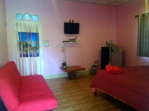a living room with a red couch and a refrigerator at Baan Benjathip in Amphawa