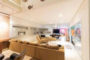 a large living room with a large couch and a tv at Casa de temporada com piscina in Peruíbe