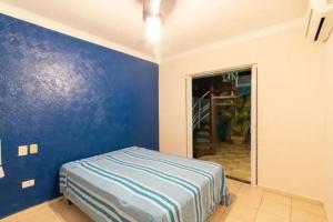 a room with a blue wall with a bed in it at Casa de temporada com piscina in Peruíbe +12 photos