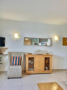 a living room with a chair and a wooden cabinet at Bayview Apartment 106 in Albufeira +16 photos