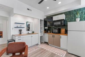 a kitchen with white cabinets and a chair and a refrigerator at Abstract Haven | Stylish 1BR by Tower Grove in Saint Louis