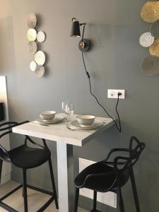 a dining room table with two chairs and a light switch at Le logis de Niort Appart Hôtel Le bis in Niort +3 photos