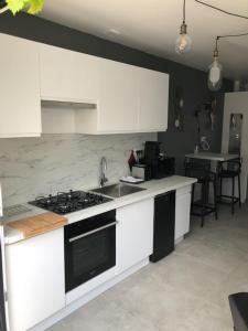 a kitchen with white cabinets and a stove top oven at Le logis de Niort Appart Hôtel Le bis in Niort