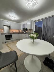 a kitchen with a white table with a vase of flowers on it at Haven at Chafford Hundred in West Thurrock