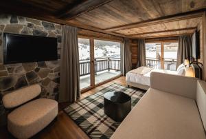 a room with a bed and a tv and a couch at Mont Chalet Nevada - Hotel & Spa in Livigno