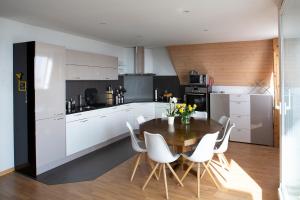 a kitchen with a wooden table and white chairs at City centre with lake view in Neuchâtel