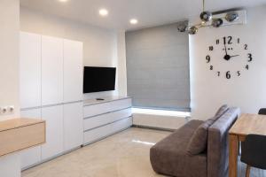 a living room with a couch and a clock on the wall at ApartPlus - Затишні апартаменти in Dnipro