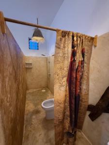 a bathroom with a toilet and a shower curtain at Carpe Diem Nungwi in Nungwi