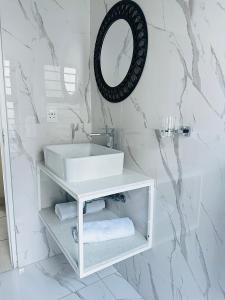 a white bathroom with a sink and a mirror at Sweet Daisies Apartment in Mbabane +63 photos