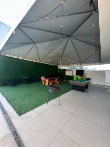 a large tent with a ping pong table and a green floor at Casa Premium com Jacuzzi e Churrasqueira in Palhoça