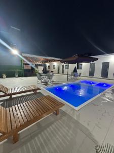 a swimming pool with two benches on a patio at night at Casa Premium com Jacuzzi e Churrasqueira in Palhoça +10 photos