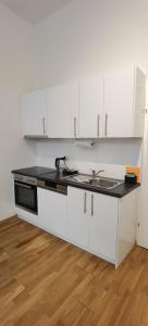 eine Küche mit weißen Schränken und einer schwarzen Arbeitsplatte in der Unterkunft Amarilis - Dolce Duo Homes in Wien