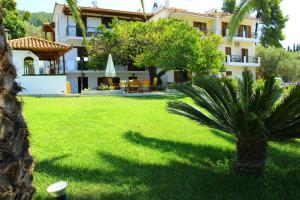 a house with a palm tree in a yard at Olympion Apartments in Stafylos