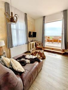 a living room with a couch and a large window at Hotel Fresena in Baltrum