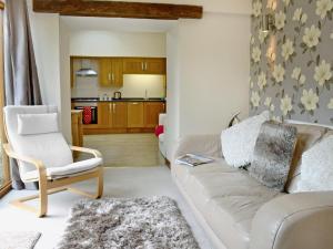 a living room with a white couch and a chair at Black Thorn Cottage in Falmouth