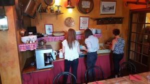 three women standing at a counter in a restaurant at L'Hôtel de la Taverne in Étretat