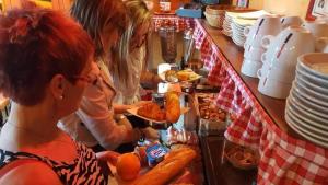 two women standing at a counter preparing food at L'Hôtel de la Taverne in Étretat