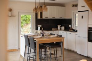 a kitchen with a wooden table and chairs in a kitchen at Escapade Boisée in Vencimont