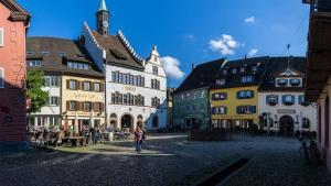 a group of people walking through a street with buildings at Goethe Schwarzwald Boutiquehotel in Staufen im Breisgau