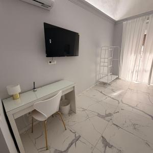 a white room with a desk and a television on a wall at Vulcano Rooms 3 in Catania