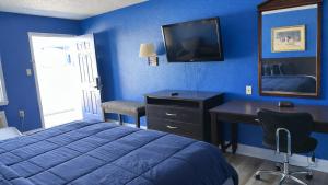 a blue bedroom with a bed and a desk and a television at Apollo Lodge and RV Park in Fairfield