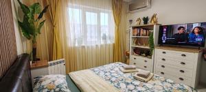 a bedroom with a bed with a television on a dresser at Abel Luxury Home in Constanţa