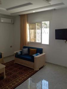 a living room with a blue couch and a television at CHEZ ALAA Kelibia in Kelibia