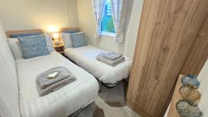 two twin beds in a small room with a window at Cornwall Caravan Retreat 3 Crantock in Crantock +45 photos