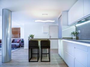 a kitchen with white cabinets and a table with two chairs at Urban Waves by Hello Homes Sitges in Sitges