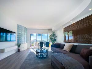 a living room with a couch and a brick wall at Urban Waves by Hello Homes Sitges in Sitges +15 photos