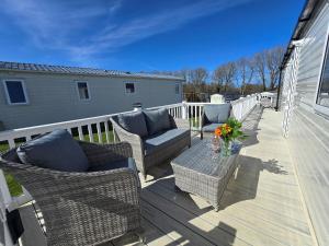 a patio with wicker chairs and a table on a deck at Cornwall Caravan Retreat 3 Crantock in Crantock