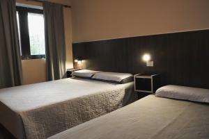 a hotel room with two beds and a window at Hotel Haití in San Miguel de Tucumán