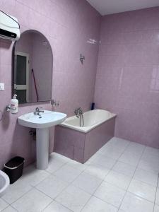 a pink bathroom with a sink and a bath tub and a sink at Hostel Villa EFES Private Rooms in Tirana +6 photos