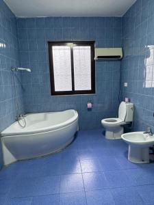 a blue tiled bathroom with a tub and a toilet at Hostel Villa EFES Private Rooms in Tirana