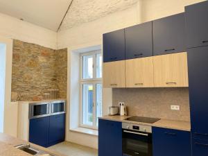 a kitchen with blue cabinets and a stone wall at Bagolyvár Fogadó- Újfalusy Márton Vendégház in Zirc